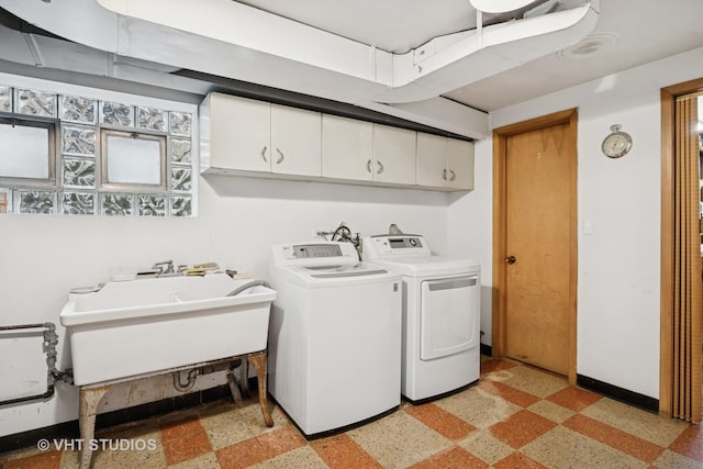 clothes washing area with a sink, baseboards, cabinet space, and washer and dryer