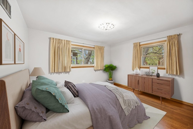bedroom featuring visible vents, baseboards, and wood finished floors