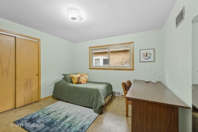 bedroom featuring baseboards, visible vents, and wood finished floors