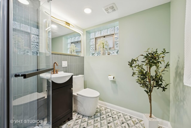 bathroom featuring visible vents, tile walls, vanity, baseboards, and toilet