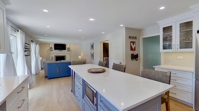1938 Keim Dr, Wheaton, IL 60189 - kitchen with stainless steel microwave, light wood-type flooring, a fireplace, light countertops, and blue cabinetry