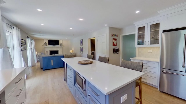 1938 Keim Dr, Wheaton, IL 60189 - kitchen featuring appliances with stainless steel finishes, white cabinetry, a breakfast bar area, light wood-type flooring, and glass insert cabinets