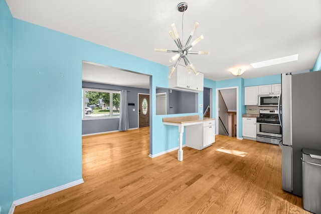 28W521 Donald Ave, West Chicago, IL 60185 - kitchen featuring stainless steel appliances, a skylight, a chandelier, white cabinets, and a peninsula