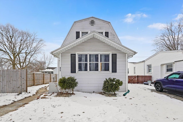 dutch colonial with fence and a gambrel roof