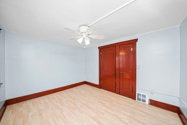 unfurnished bedroom featuring visible vents, ceiling fan, a closet, baseboards, and wood finished floors