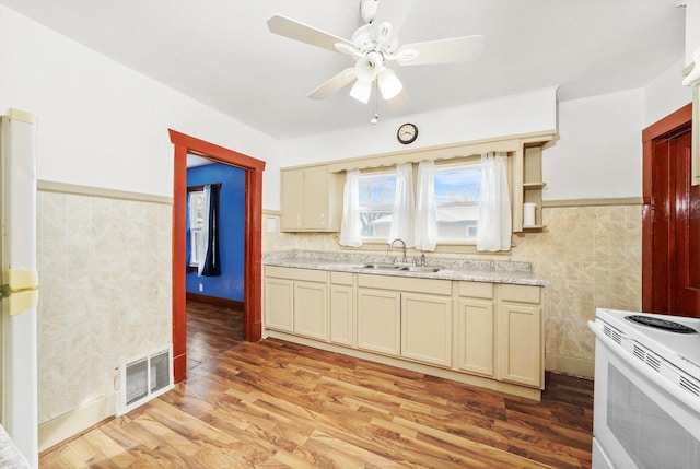 kitchen with visible vents, electric range, a sink, light wood-type flooring, and a ceiling fan