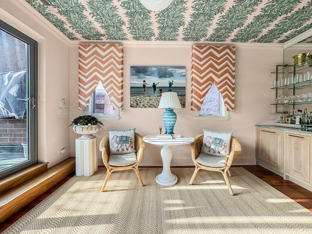 sitting room with bar area, wallpapered walls, wood finished floors, and a wealth of natural light