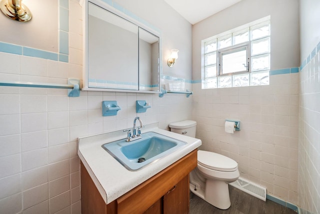 525 Mackinaw Ave, Calumet City, IL 60409 - bathroom with visible vents, wood finished floors, toilet, tile walls, and a wainscoted wall