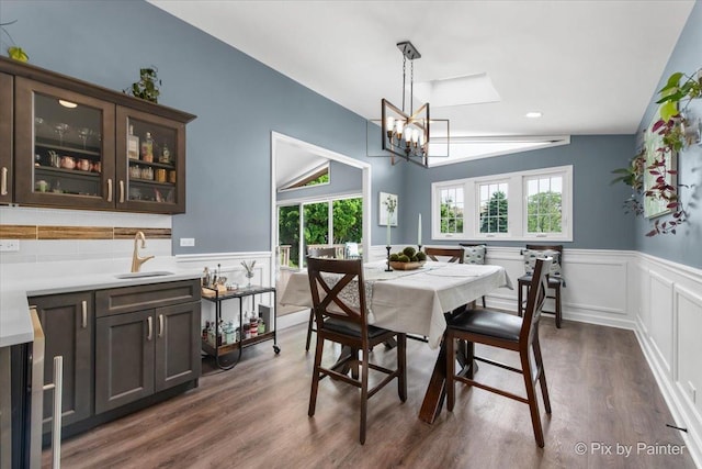 6561 Dunham Rd, Downers Grove, IL 60515 - dining area with a chandelier, a wainscoted wall, dark wood-style floors, lofted ceiling, and a decorative wall