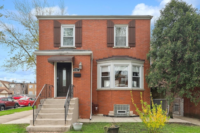 view of front facade featuring brick siding, fence, central AC unit, and a gate