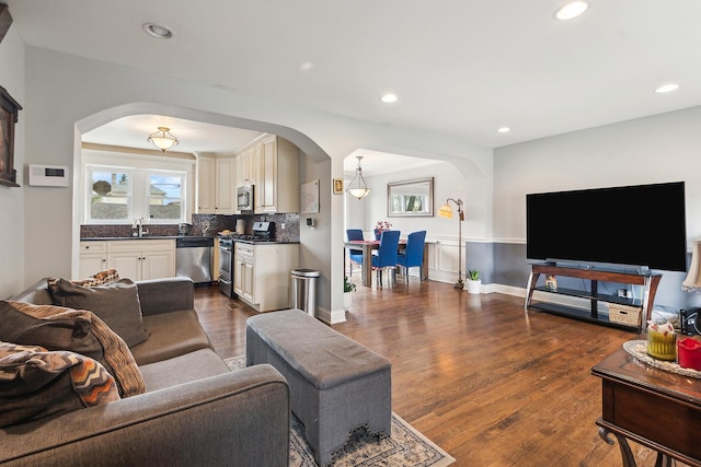 living area featuring dark wood-type flooring, arched walkways, and recessed lighting