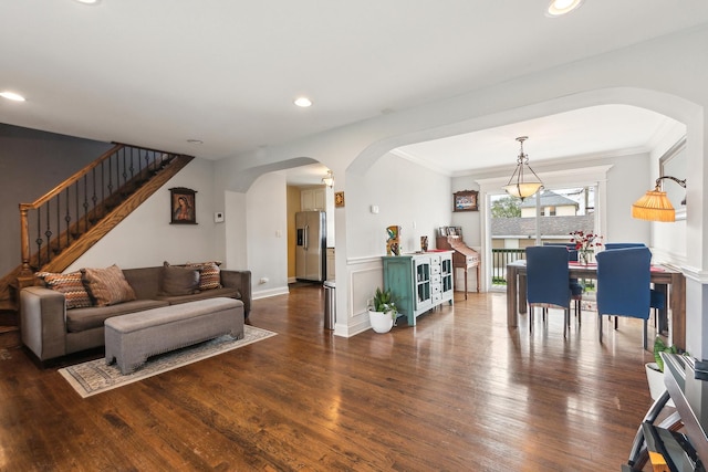 living room featuring arched walkways, wood finished floors, and ornamental molding