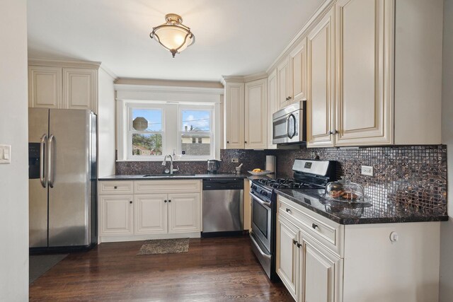 kitchen with a sink, appliances with stainless steel finishes, decorative backsplash, and cream cabinetry