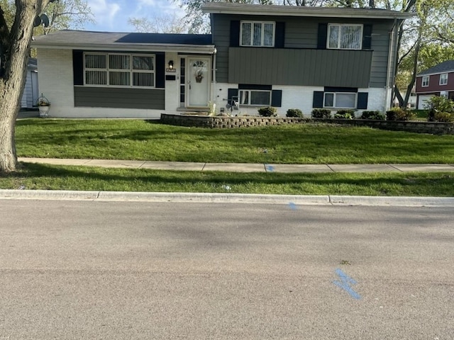 tri-level home with brick siding and a front lawn