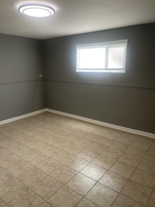 unfurnished room with a wainscoted wall and baseboards