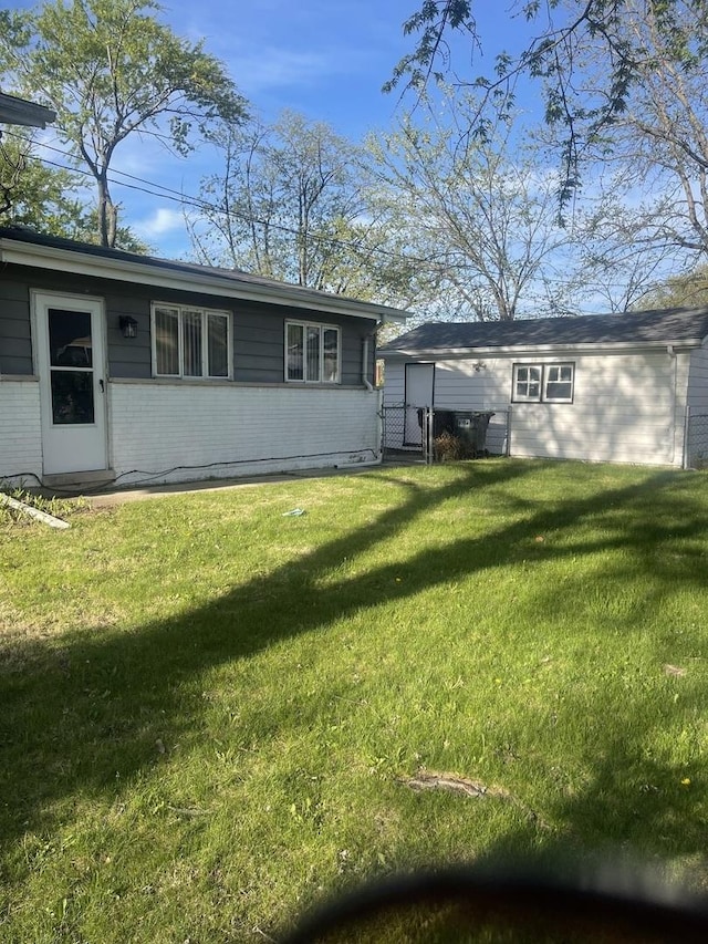 rear view of property featuring brick siding, a gate, and a lawn