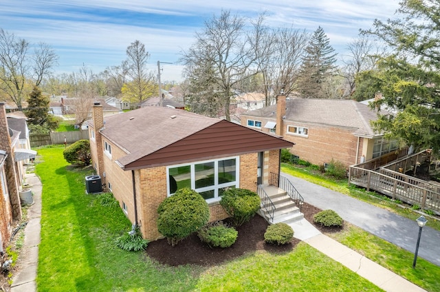 exterior space with fence, a residential view, brick siding, central AC unit, and a lawn