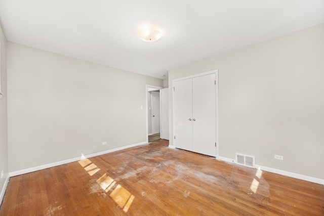unfurnished bedroom featuring a closet, baseboards, visible vents, and light wood-style floors
