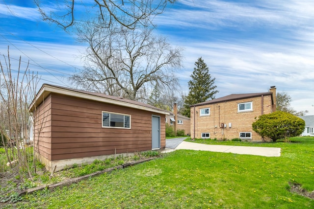 rear view of property with a lawn and an outdoor structure
