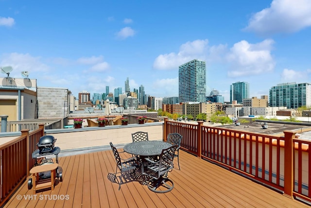 wooden deck featuring a skyline view, outdoor dining space, and a grill