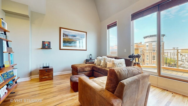living area featuring light wood-style floors, baseboards, and lofted ceiling