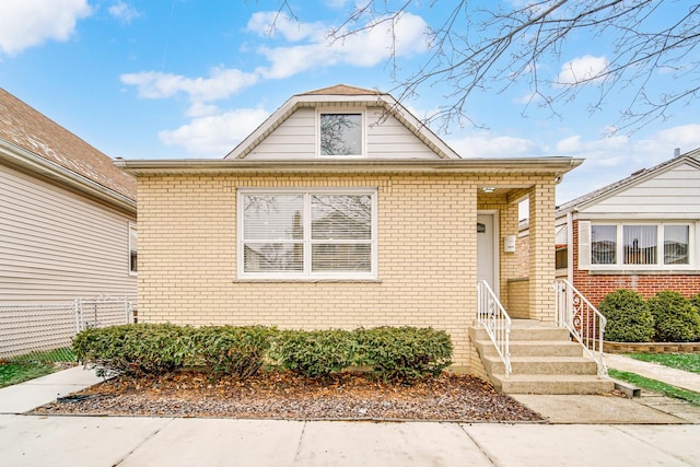 bungalow-style home featuring brick siding, fence, and entry steps