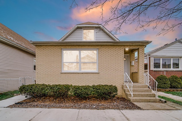 bungalow-style home with fence and brick siding