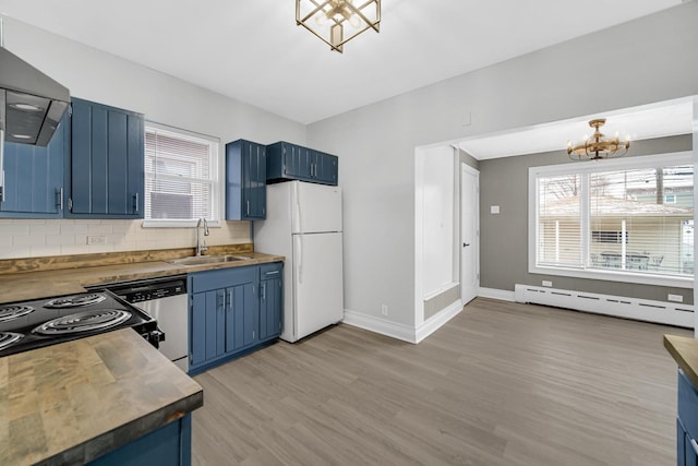 kitchen with an inviting chandelier, a sink, baseboard heating, blue cabinetry, and freestanding refrigerator