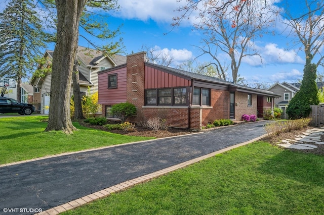 view of front facade with brick siding, board and batten siding, aphalt driveway, and a front yard