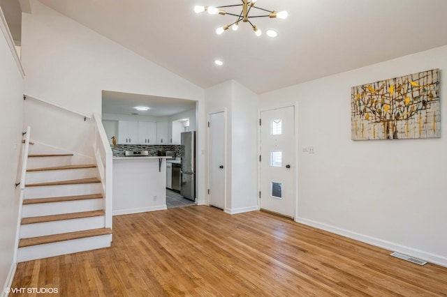 foyer with an inviting chandelier, light wood-style floors, visible vents, and stairway