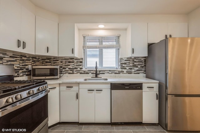 kitchen with backsplash, appliances with stainless steel finishes, a sink, light countertops, and white cabinetry