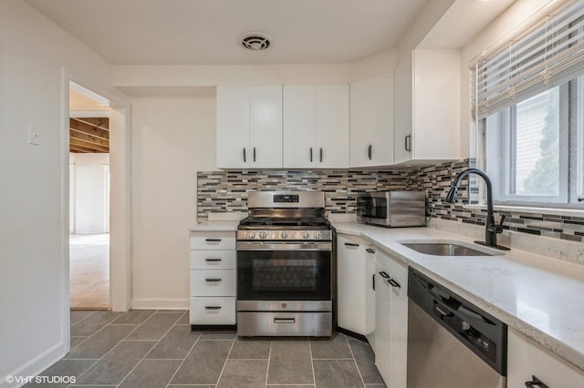 kitchen featuring a sink, white cabinets, backsplash, and stainless steel appliances