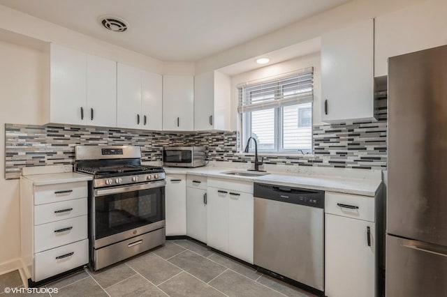kitchen featuring a sink, white cabinetry, tasteful backsplash, and stainless steel appliances