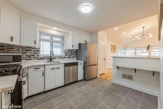 kitchen featuring a sink, light countertops, stainless steel appliances, backsplash, and visible vents