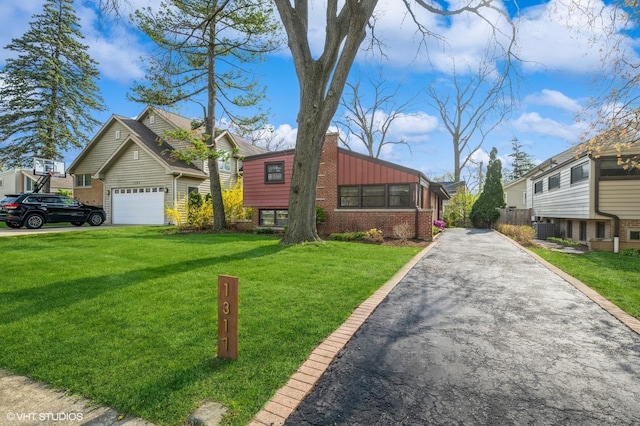 view of front of property featuring a chimney, driveway, a front lawn, and brick siding