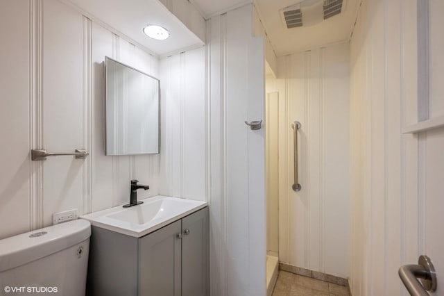 bathroom with visible vents, vanity, toilet, walk in shower, and tile patterned floors