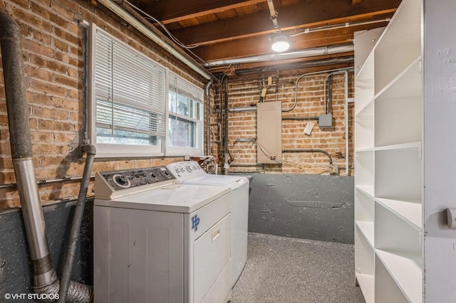 laundry room featuring washing machine and dryer and brick wall