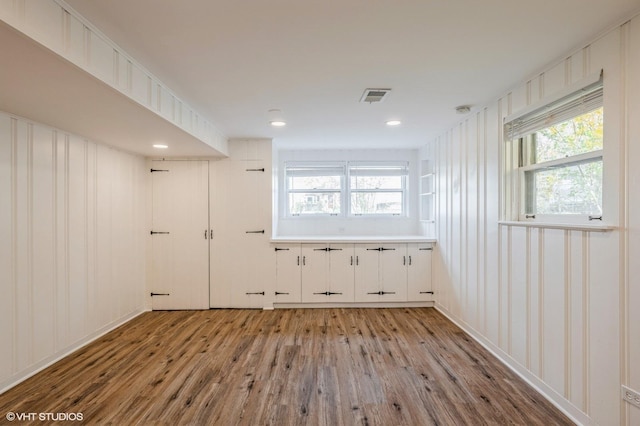 spare room featuring a decorative wall, visible vents, a healthy amount of sunlight, and light wood-style floors