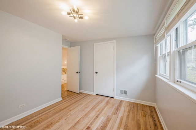 unfurnished bedroom with visible vents, light wood finished floors, baseboards, and a closet