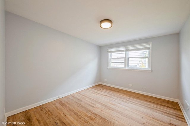unfurnished room with baseboards and light wood-type flooring