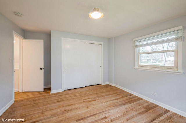 unfurnished bedroom with light wood-style floors, baseboards, and a closet