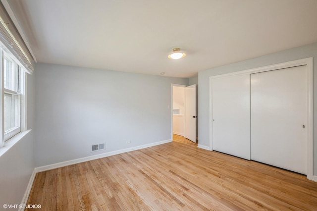 unfurnished bedroom featuring visible vents, light wood-style floors, baseboards, and a closet