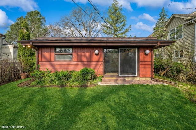 rear view of property featuring a yard, fence, and board and batten siding