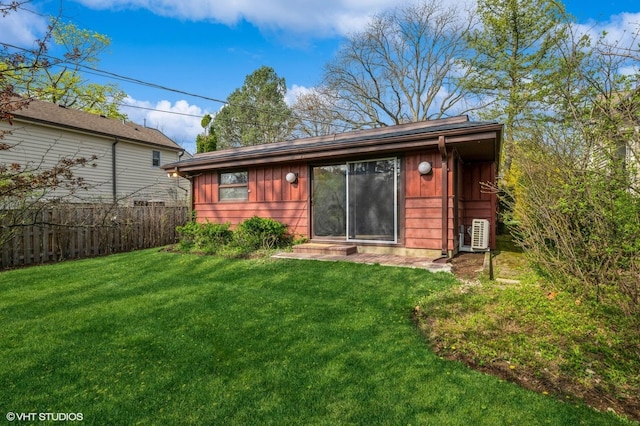 rear view of property with board and batten siding, a lawn, fence, and entry steps