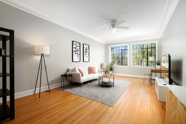 living area with crown molding, baseboards, a ceiling fan, and light wood finished floors