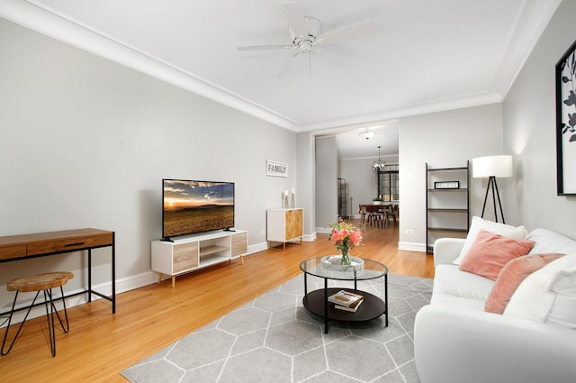 living area featuring crown molding, ceiling fan, baseboards, and wood finished floors