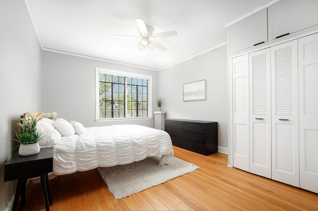 bedroom with ceiling fan, crown molding, baseboards, a closet, and light wood-style floors