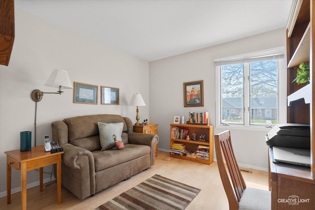 living area featuring baseboards, a wealth of natural light, and light wood-style flooring
