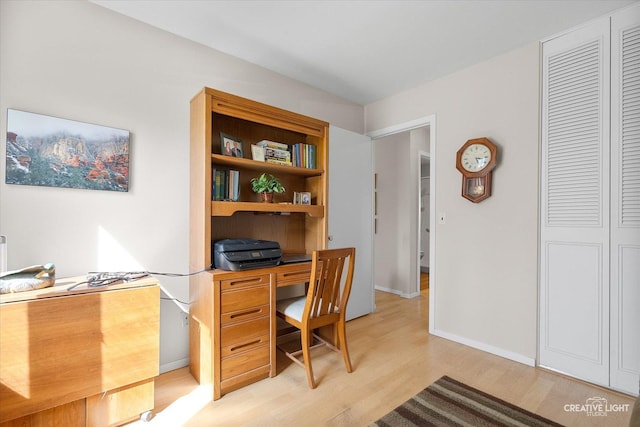 office space with baseboards and light wood finished floors