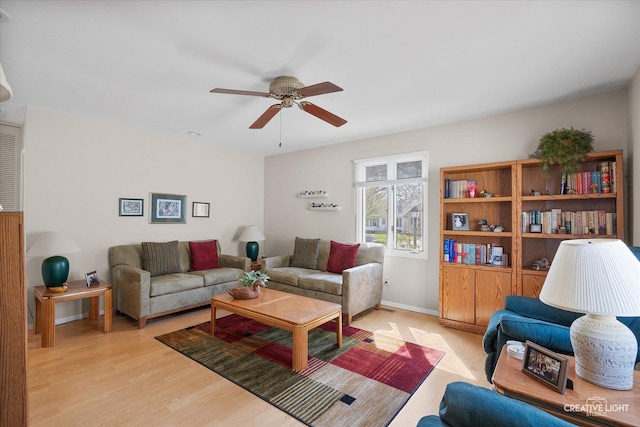living area with a ceiling fan, baseboards, and light wood-type flooring